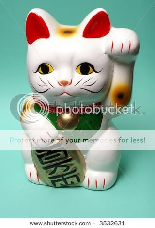 stock-photo-maneki-neko-lucky-cat-on-a-green-background-a-common-japanese-sculpture-often-made-of-porcelain-3532631